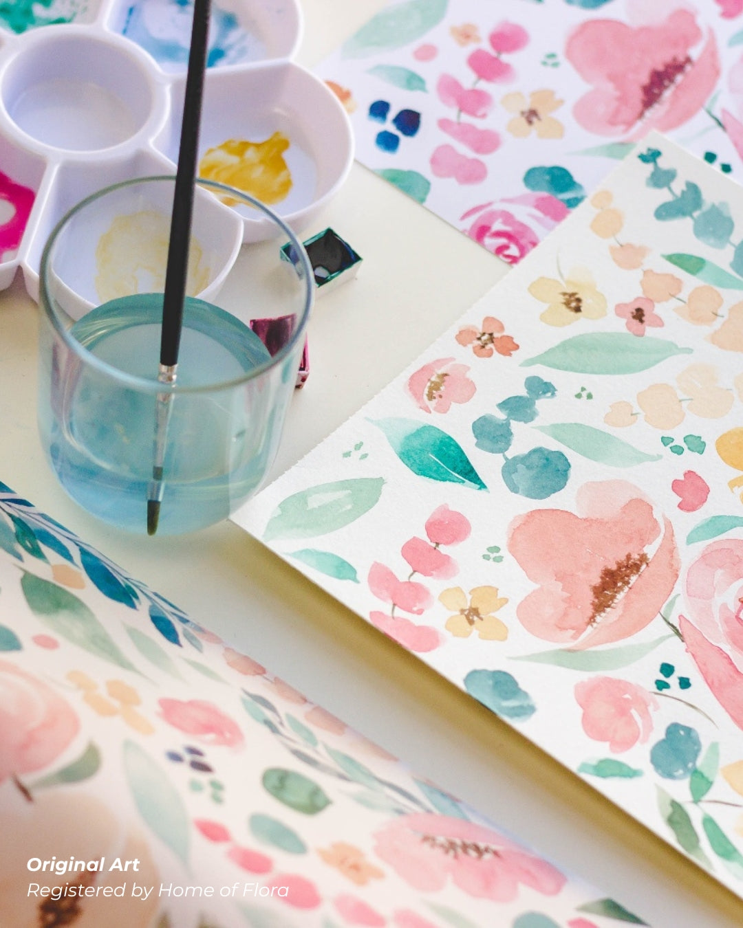 Colorful watercolor flowers on a piece of paper with a glass of water and paintbrush.