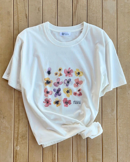 White t-shirt with colorful floral design on a wooden surface