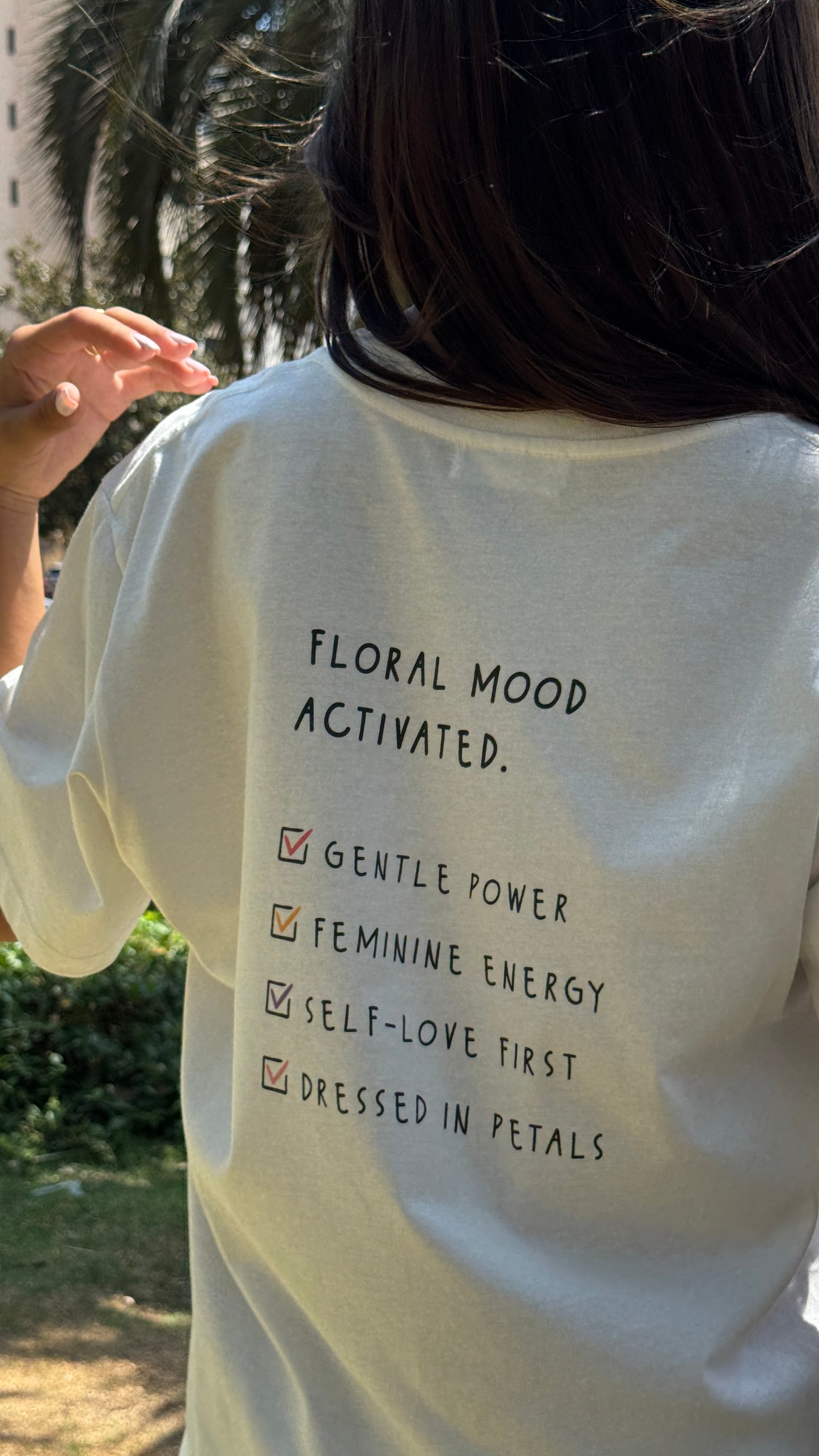 Person wearing a white t-shirt with text on the back in an outdoor setting