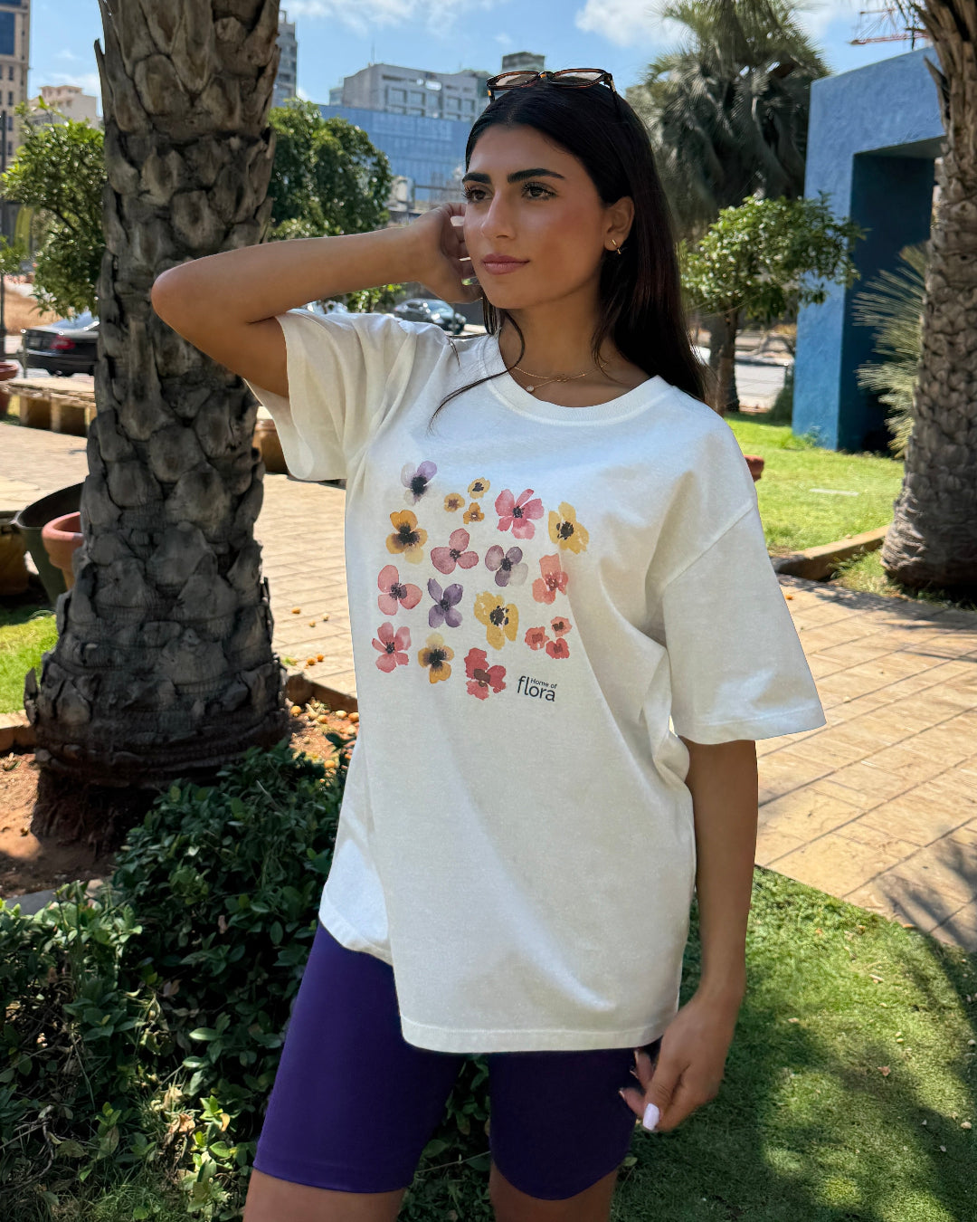 Woman wearing a white t-shirt with floral design outdoors near palm trees