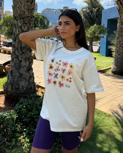 Woman wearing a white t-shirt with floral design outdoors near palm trees