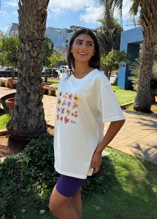 Woman wearing a white oversized t-shirt with colorful floral design outdoors.