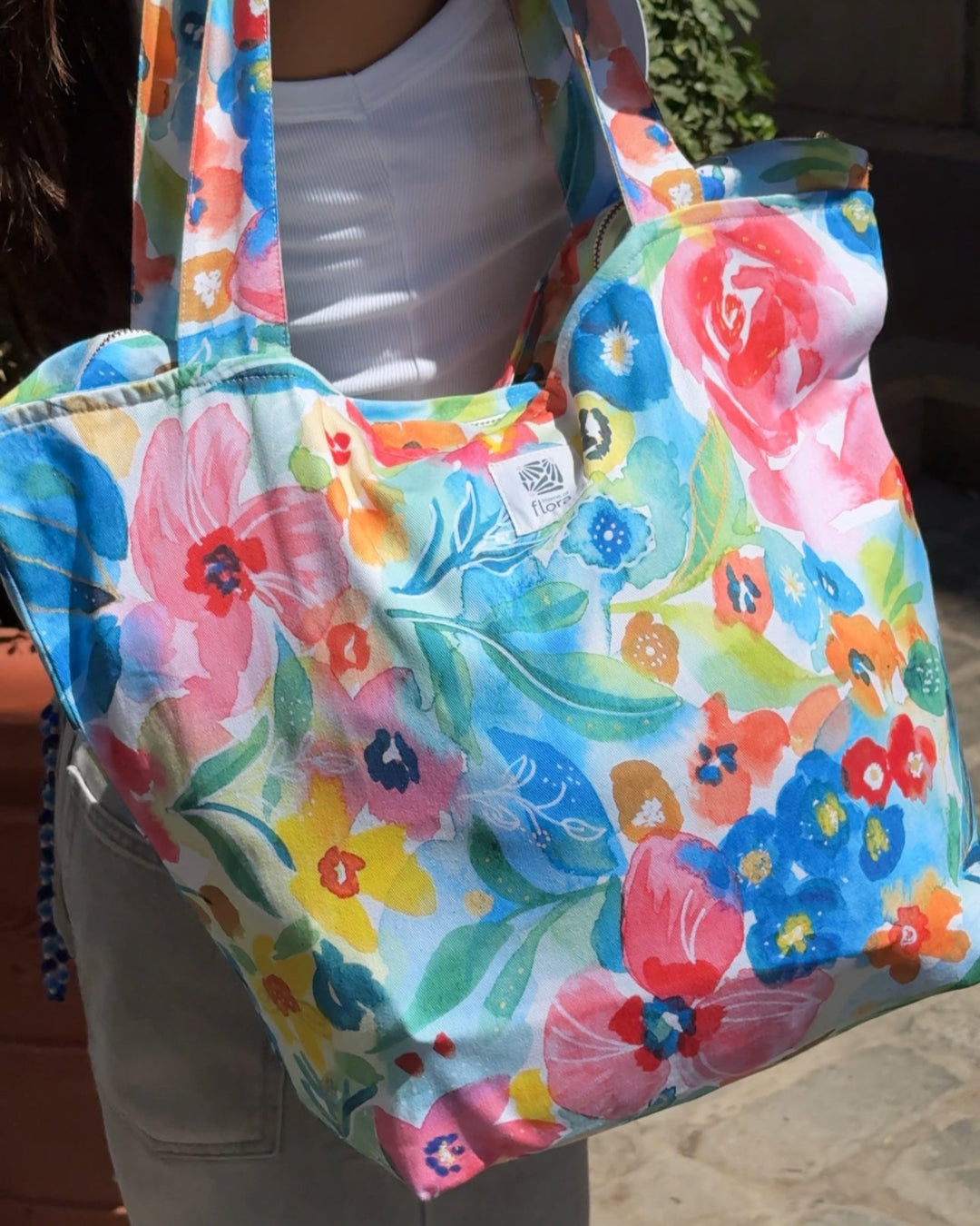 Colorful floral-patterned bag held by a person outdoors.