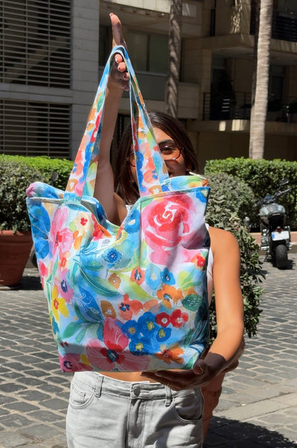 Person holding a colorful floral tote bag on a street.