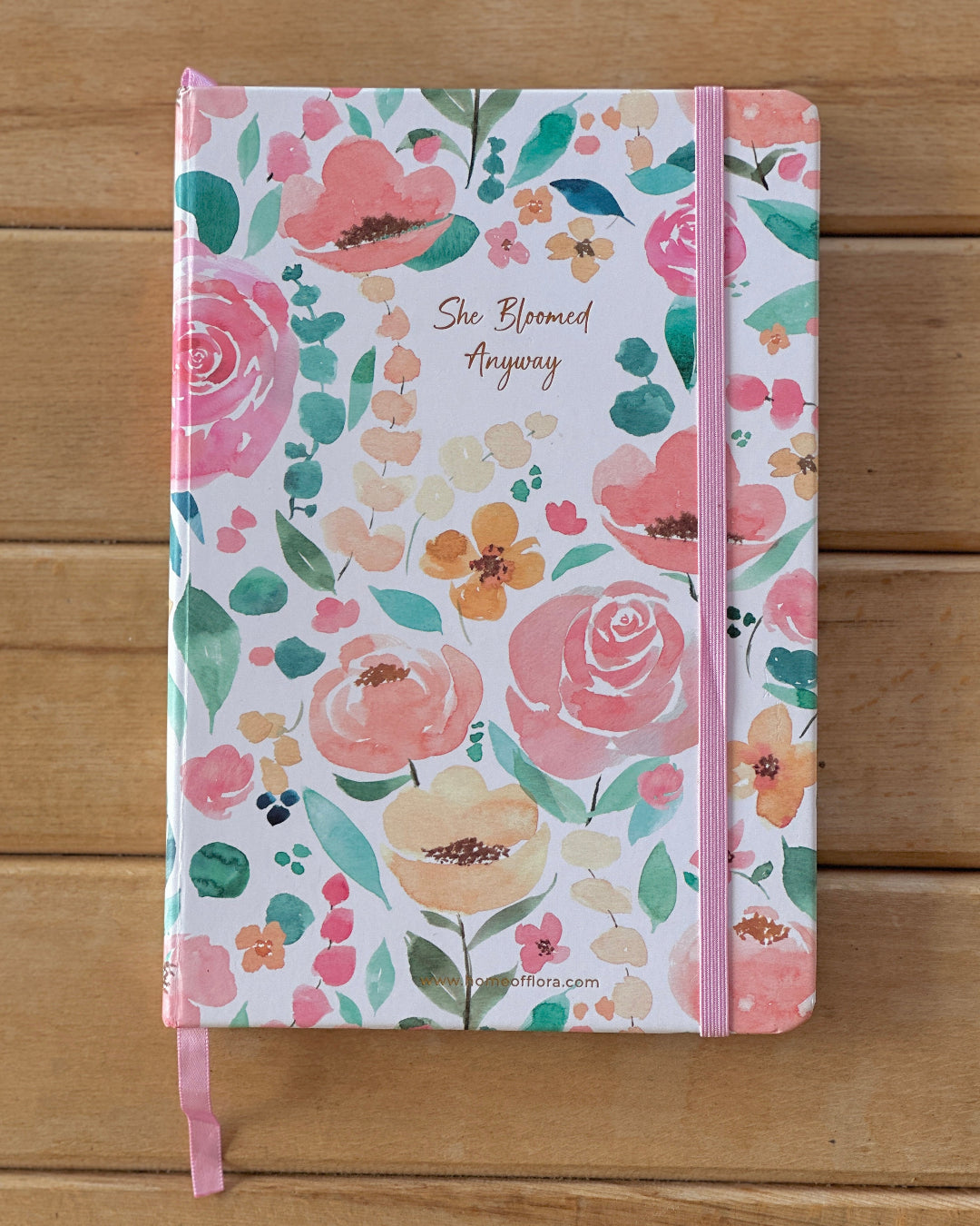 Floral notebook with pink binding on a wooden surface