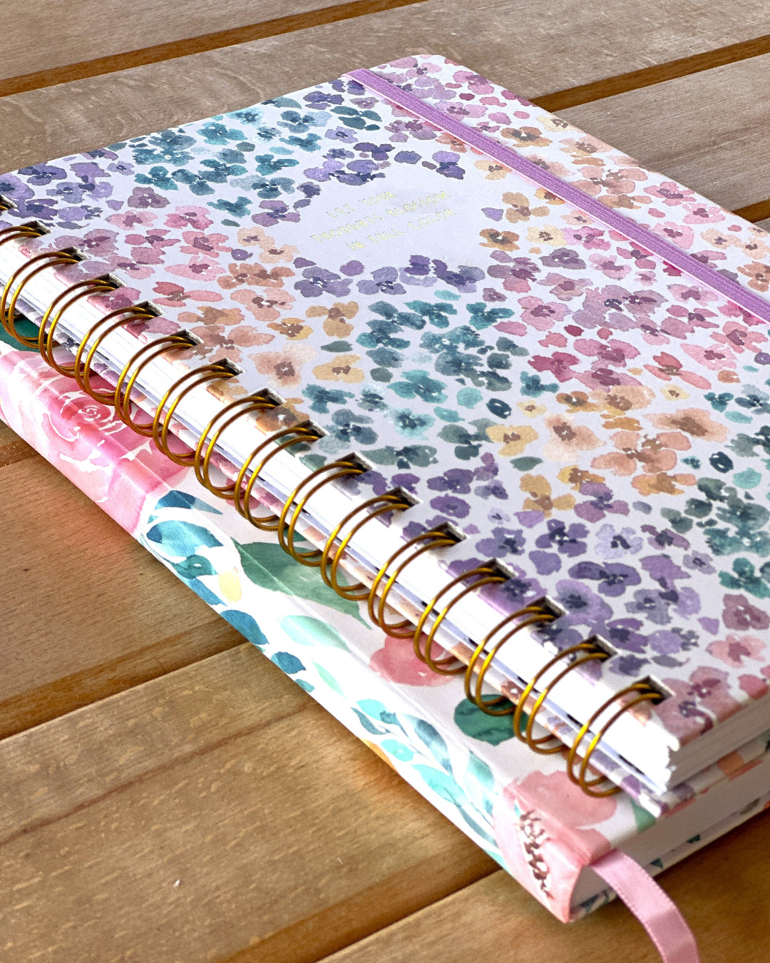 Stack of floral-patterned notebooks on a wooden surface