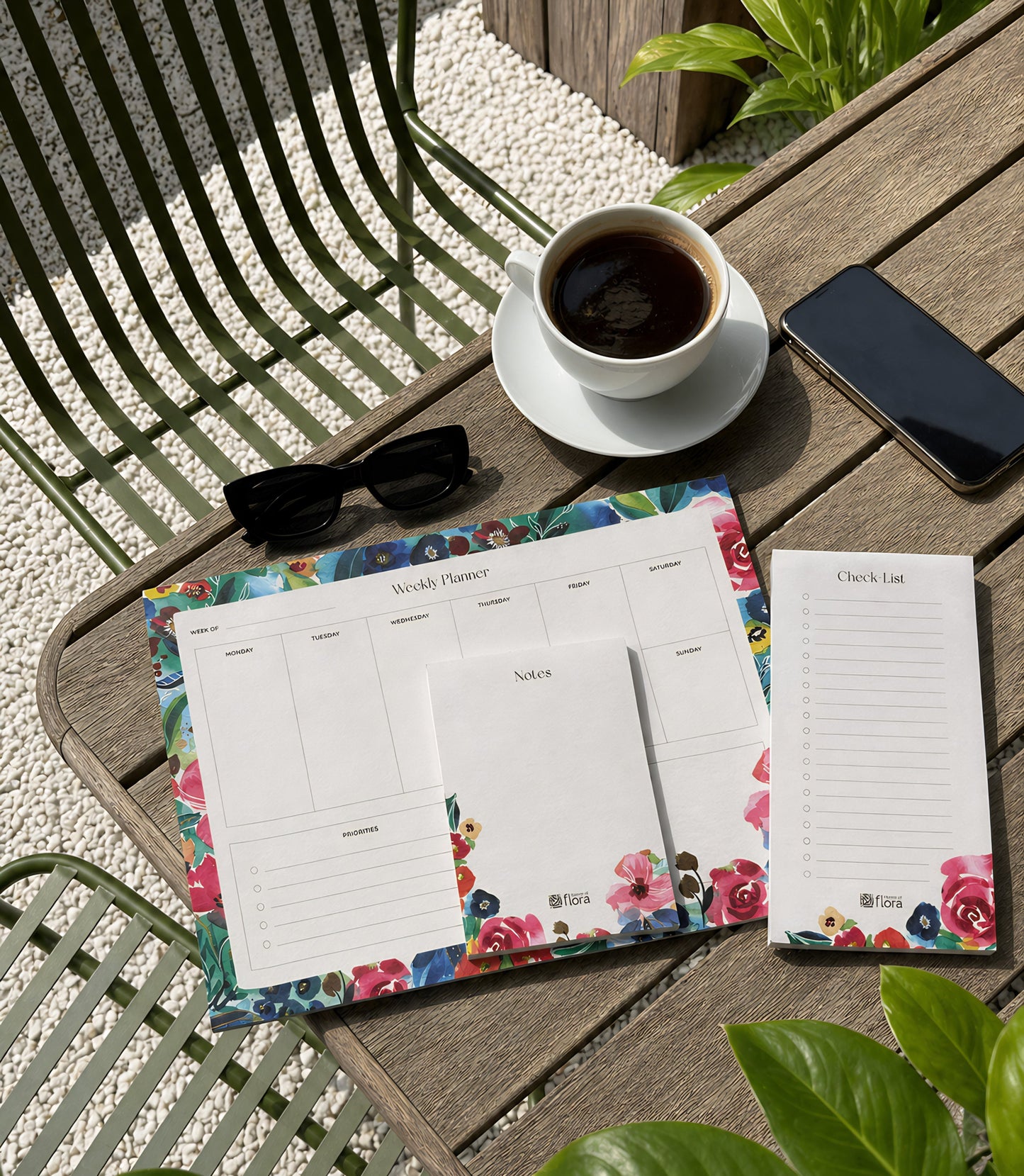 Floral planner sheets on a table with a cup of coffee, phone, and sunglasses.